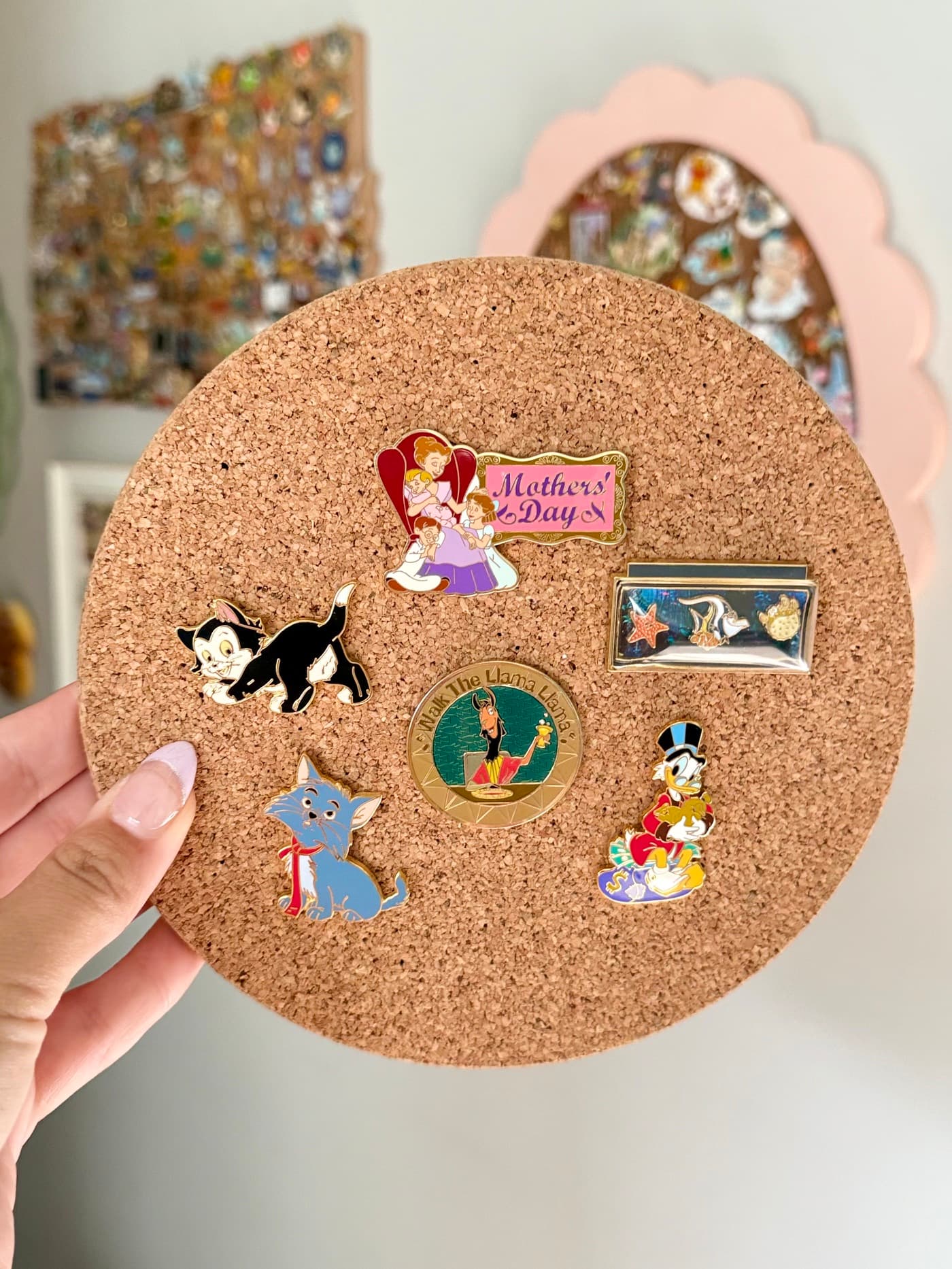 A handful of collectible enamel pins on a cork board